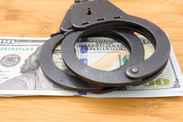 A set of handcuffs on top of two hundred dollar bills.