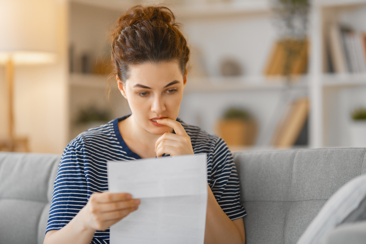 Woman looking at a piece of paper in confusion, worried about making Social Security Disability mistakes.